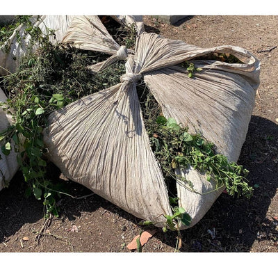 One 80x80 poly sheet bundle tied up and filled with leaves, branches, and twigs from landscaping
